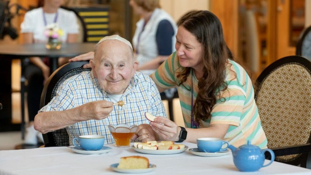 elderly man enjoying some honey and apples