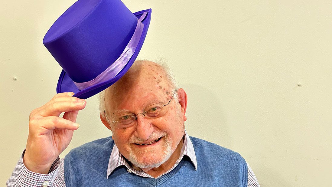 Community Centre member tipping a purple hat.