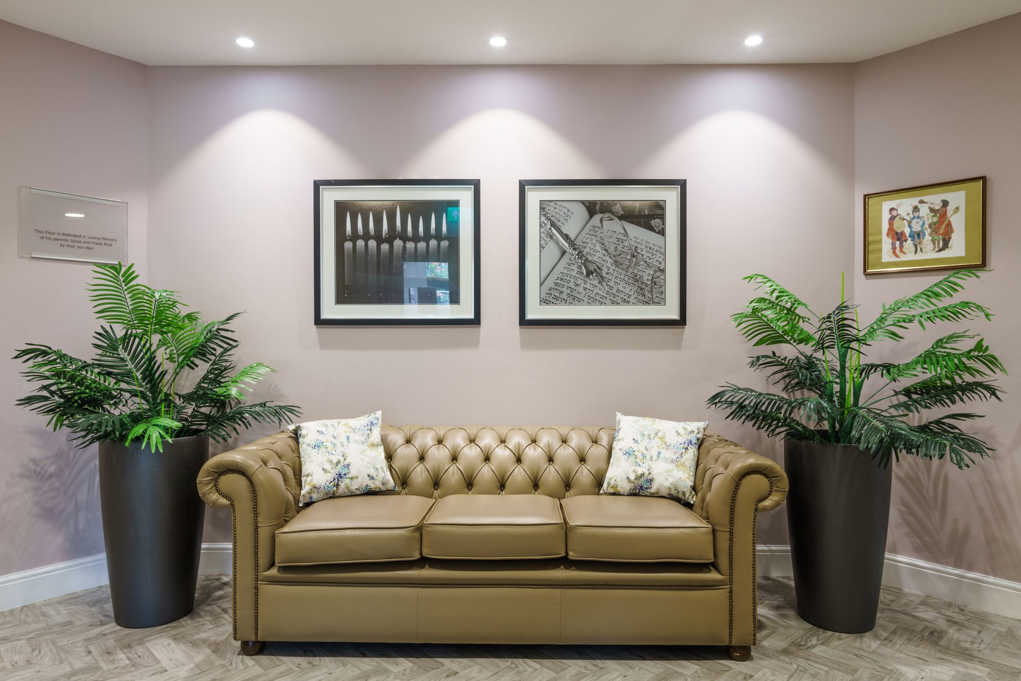 Kun Mor and George Kiss Home Seating Area A brown chesterfield sofa surrounded by plants and pictures on the wall